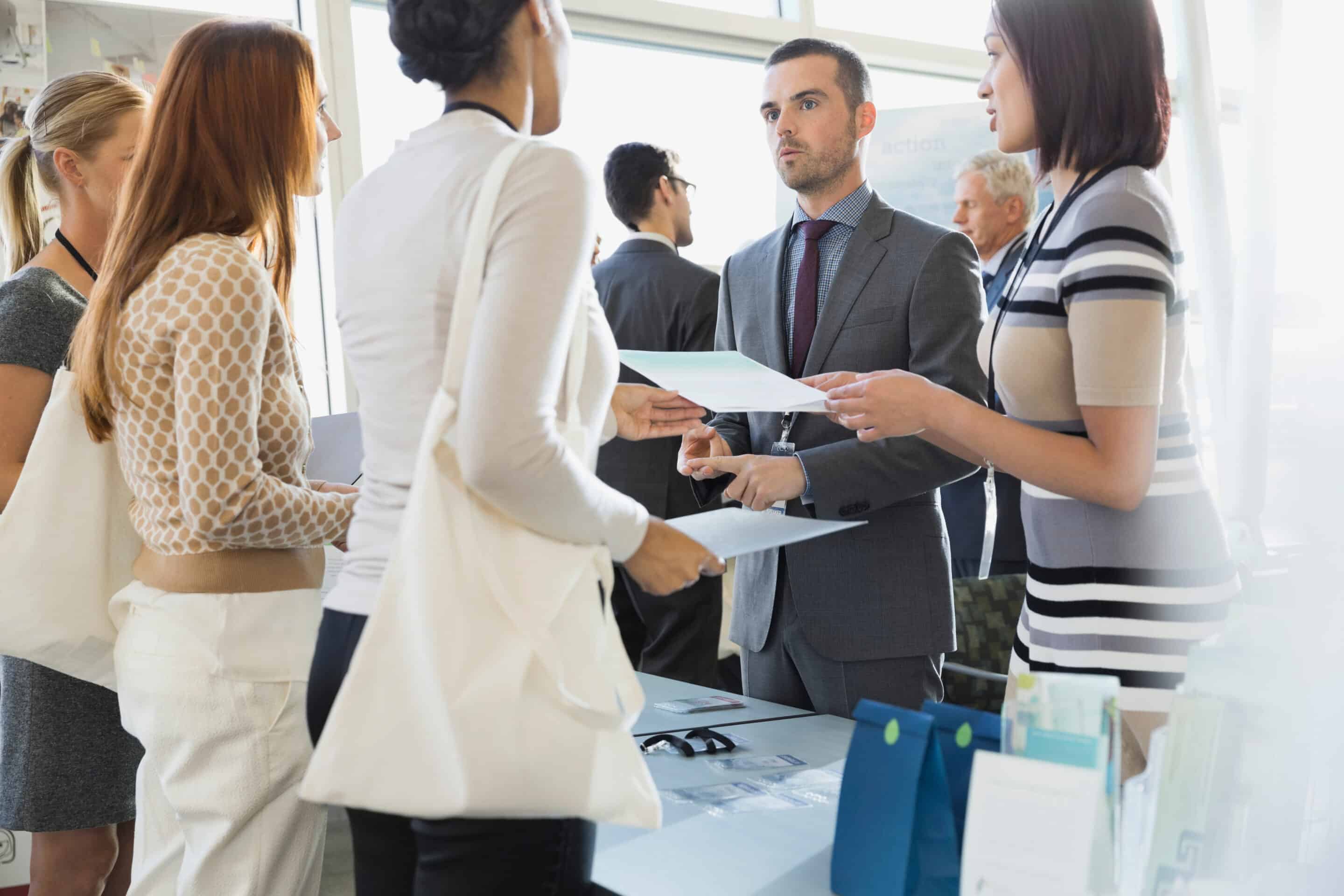 Colleagues explaining conference registration forms to attendees