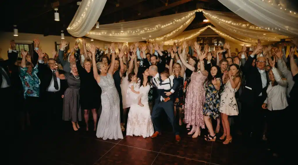 Couple kissing and dancing with wedding attendees