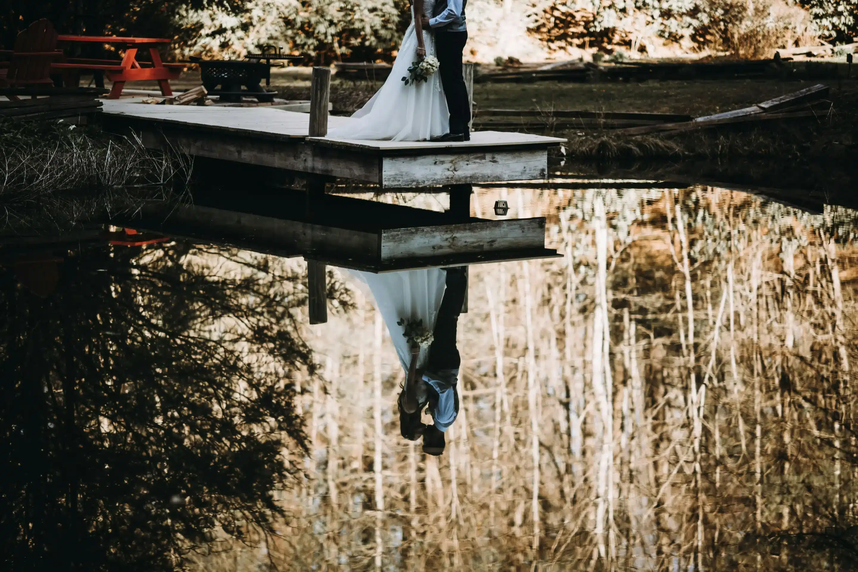 Couple kissing on a dock with a reflection in the water