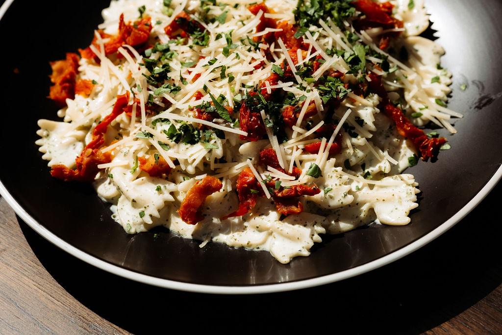 Chicken pasta dish on a black and white plate